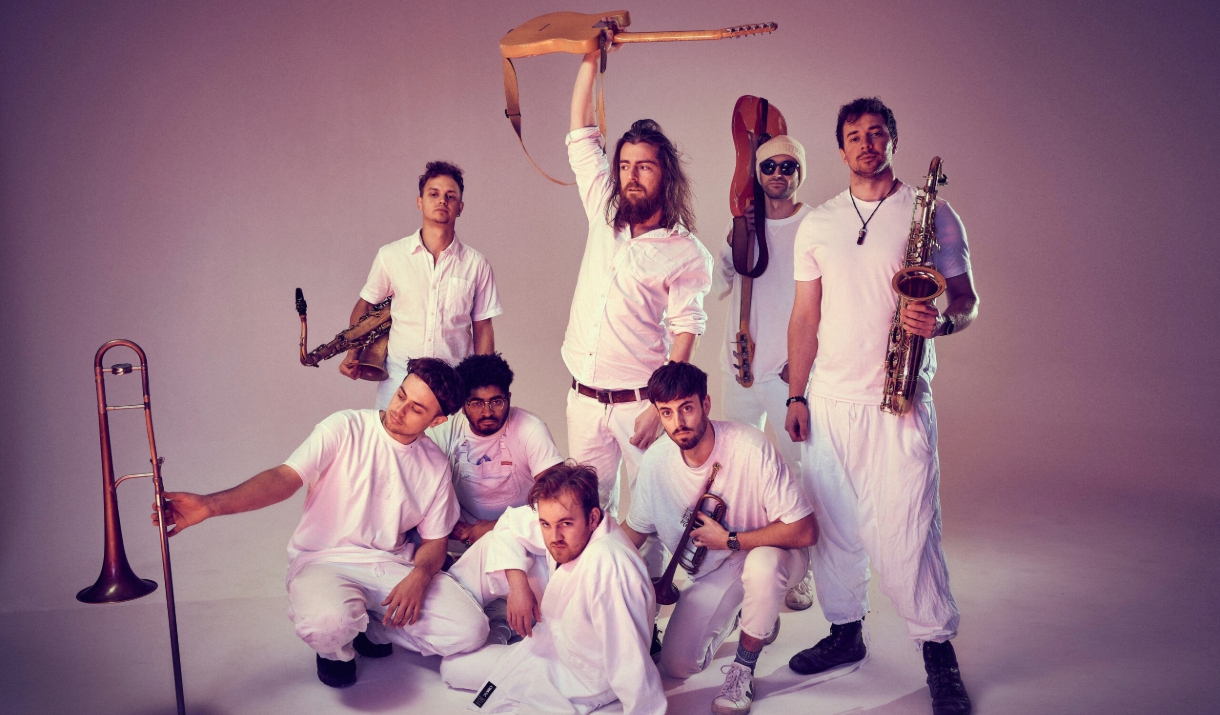 Tom McGuire and The Brassholes members posing and holding instruments wearing all white outfits