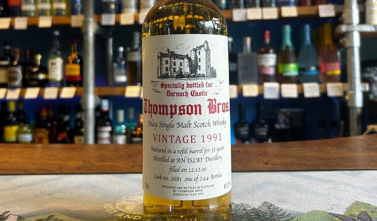 Whisky bottle with label in front of a bar shelf with various bottles