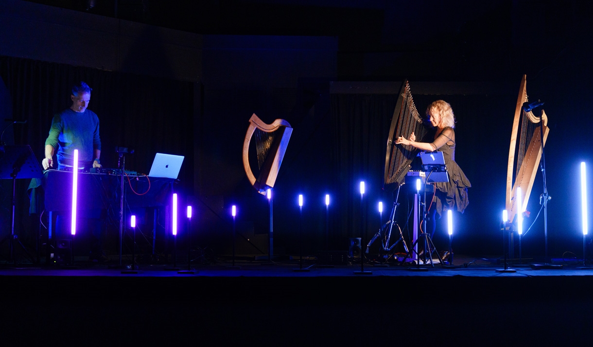 A harpist and producer on a stage