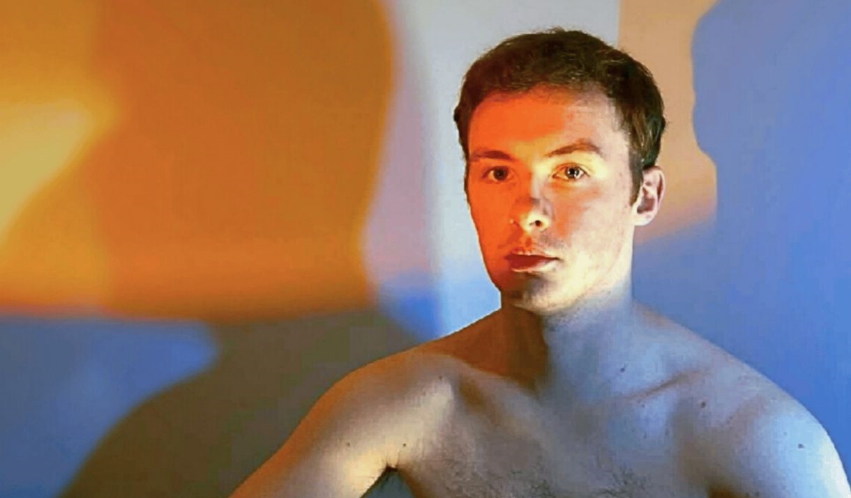 A young man sits shirtless, wearing boxing gloves, shadows bright in the background. The Sparkfest logo is in the top corner