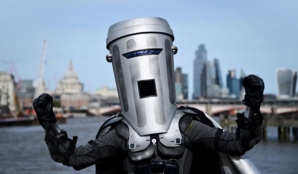 A photo of Count Binface - he has his fists raised up. In the Background is the London city skyline.