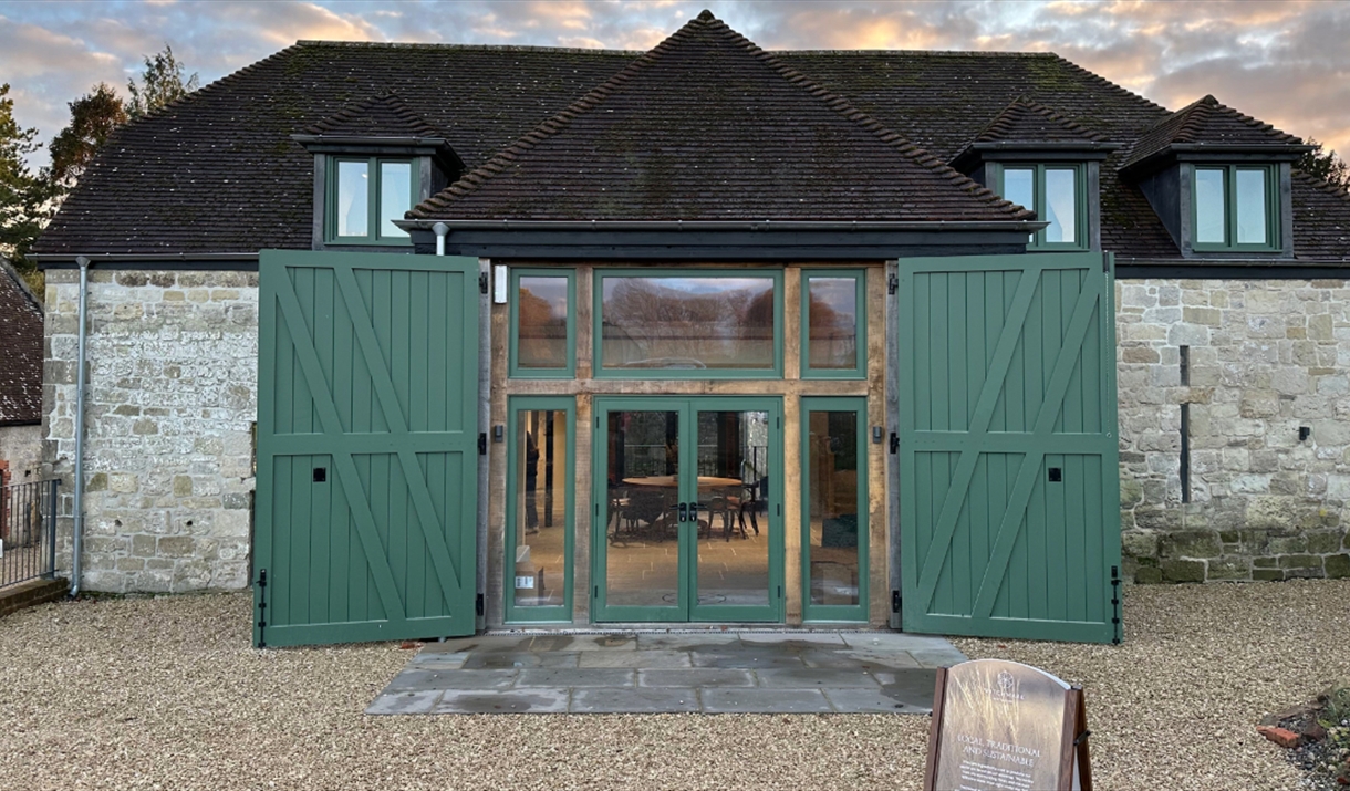 A picture of the front of witchmark distillery with its double green doors on a historic stone barn.