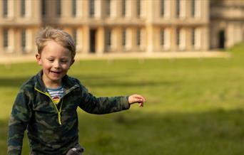 Boy running in front of a historic house