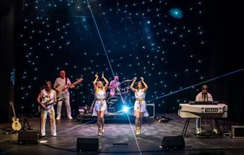 people dressed as abba, performing on a stage