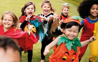 Group of children in Halloween costumes running outside