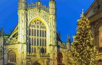 A Christmas tree lit with golden lights in front of a Church front