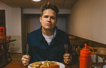 Luke Wright sat at a table with sausage and chips