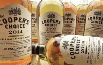 A selection of whisky bottles with brightly coloured labels from different distilleries on a white background.