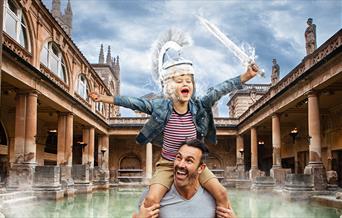 Father and son at the Roman Baths. Boy sits on fathers shoulders as the steam from the water of the Baths creates a Roman shield on his head and sword