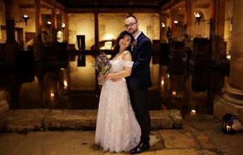 A bride and groom alongside The Great Bath at The Roman Baths