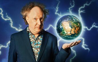 A photo of Andy Zaltzman, his holing a globe of the earth. Lighting is is shooting from the globe.