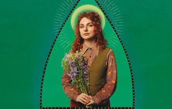 a Image on the comedian Ania Magliano - she is holing a bouquet of flowers against a green background.