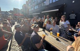 people sitting outside in the sun with a drink in hand