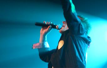 A photo of the singer for Tribute Triple Bill singing into a microphone