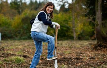 woman digging with spade in open woodland field