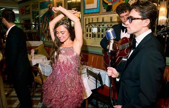 A lady in a pink 1930s style dress dancing to a live performance at The Ivy