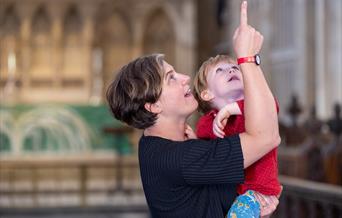 A photo of a woman holding a child and pointing up