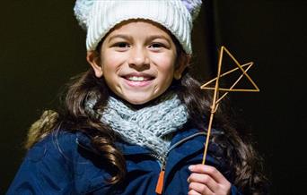 young girl holds star made from twigs