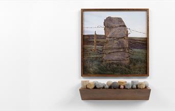 A large standing stone in landscape with barbed wire wrapped around it