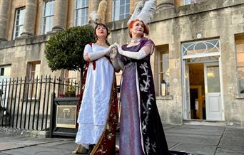 2 women dressed in Regency wear stood outside the Royal Crescent Hotel