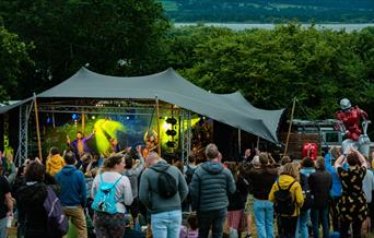 People stood in a field with a stage in the backgroun
