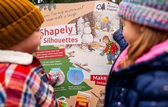 two children look at colourful Stick Man trail panel