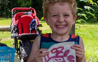 child holds up hand painting outdoors
