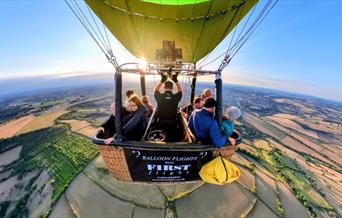View of people in a balloon basket in the whilst in the air.