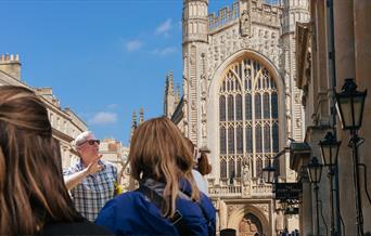 Tour guide discussing the Roman Baths while in front of the Cathedral