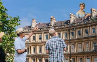 Tour guide discussing Jane Austen standing above and behind Bath architecture
