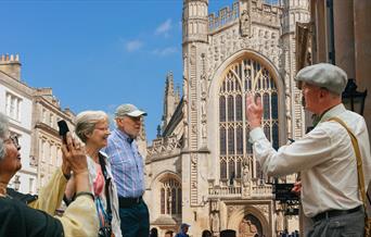 Tour guide discussing Bath Abbey in front of it with the tour group