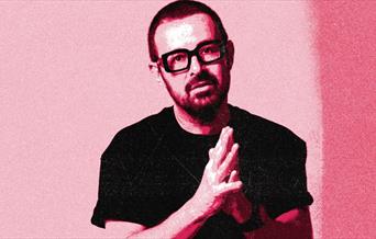 DJ Judge Jules stands with his hands together in front of his chest