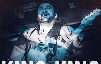 A blue-tinged image of a man playing a guitar