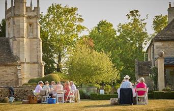 People sat outside in sunshine in countryside