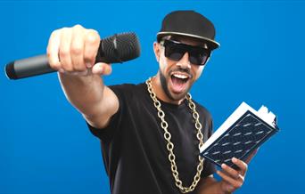 MC Grammar holding a book in one hand and a microphone in the other