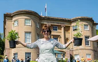 Woman holding plants in front of a Georgian Manor House