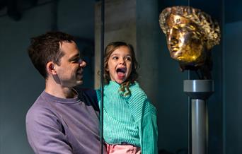child and parent looking at statue of Minerva at The Roman Baths