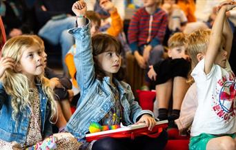 Children raising their hands at literature event