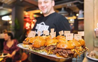 Person holding a tray of burgers