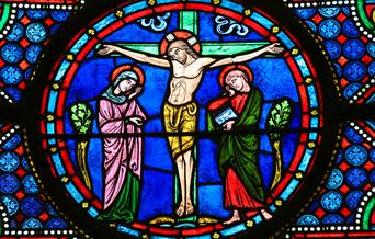 Stained glass window image of Jesus on the cross