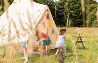 Children playing in the dress up tent in Lacock Abbey's parkland.