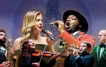 Vocalists and instrumentalists in front of a Christmas tree
