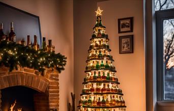A christmas tree in a cartoon style beside a fireplace and covered in layers of empty whisky bottles.
