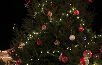 A Christmas tree with red and green baubles and twinkly lights.