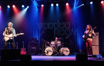 A photo of a rock band playing live on a stage