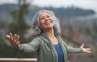 Happy older woman with arms open in nature