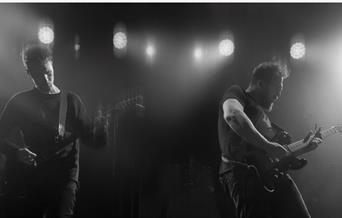 A black and white image of the duo Ben Ottewell & Ian Ball playing guitars on the stage