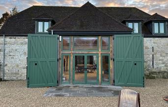 A picture of the front of witchmark distillery with its double green doors on a historic stone barn.