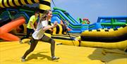 A girl running on an inflatable yellow obstacle course