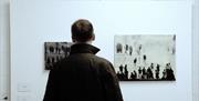 A man looking at art on the wall at Roseberry Road Studios